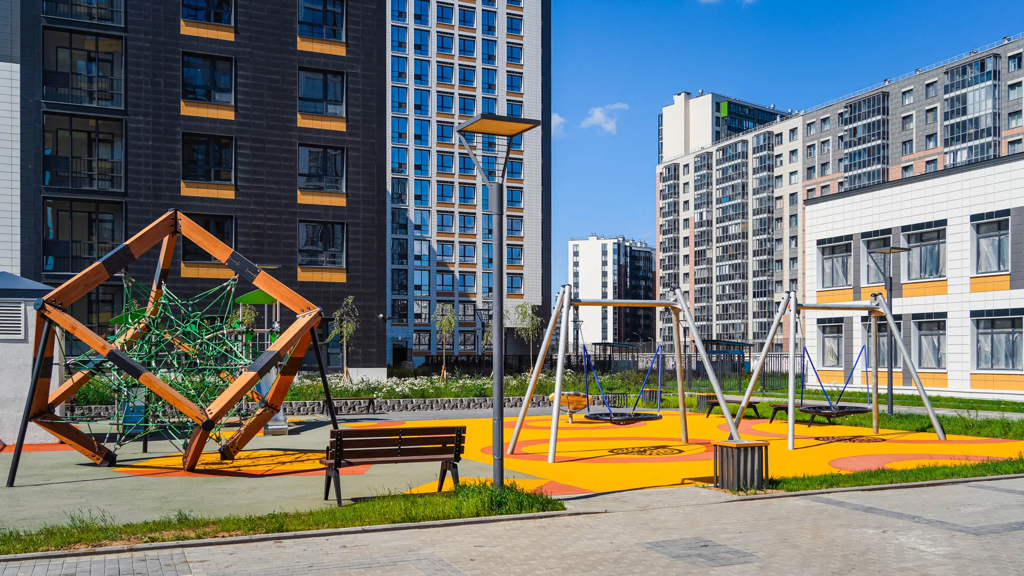 Детская площадка во дворе: деревянный игровой куб с сеткой, качели, оранжевое мягкое покрытие
