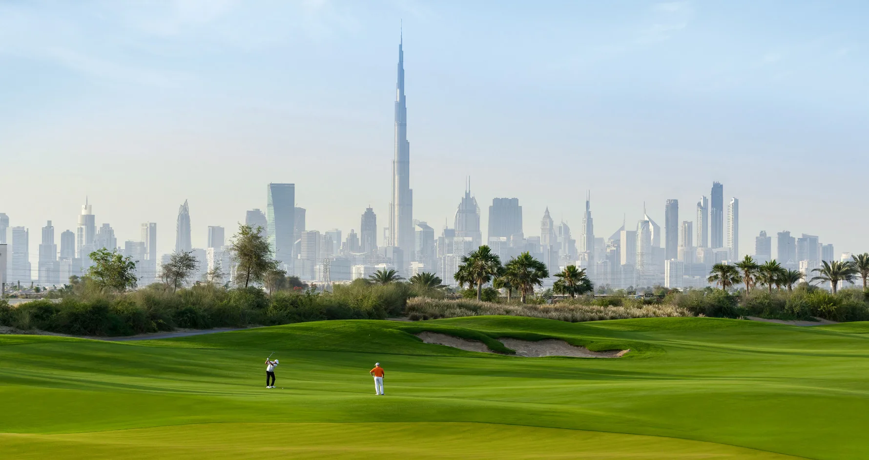 Зелёные поля Dubai Hills Estate на фоне небоскрёбов центра Дубая