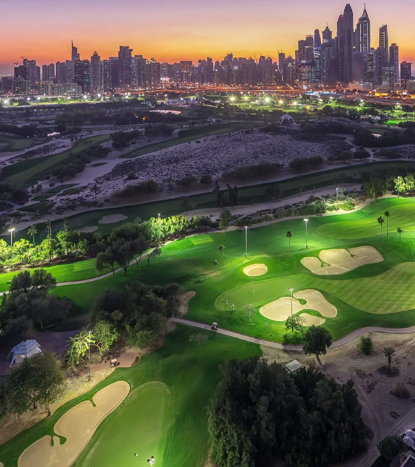 Поля Emirates Golf Course на закате, за ними небоскрёбы Марины