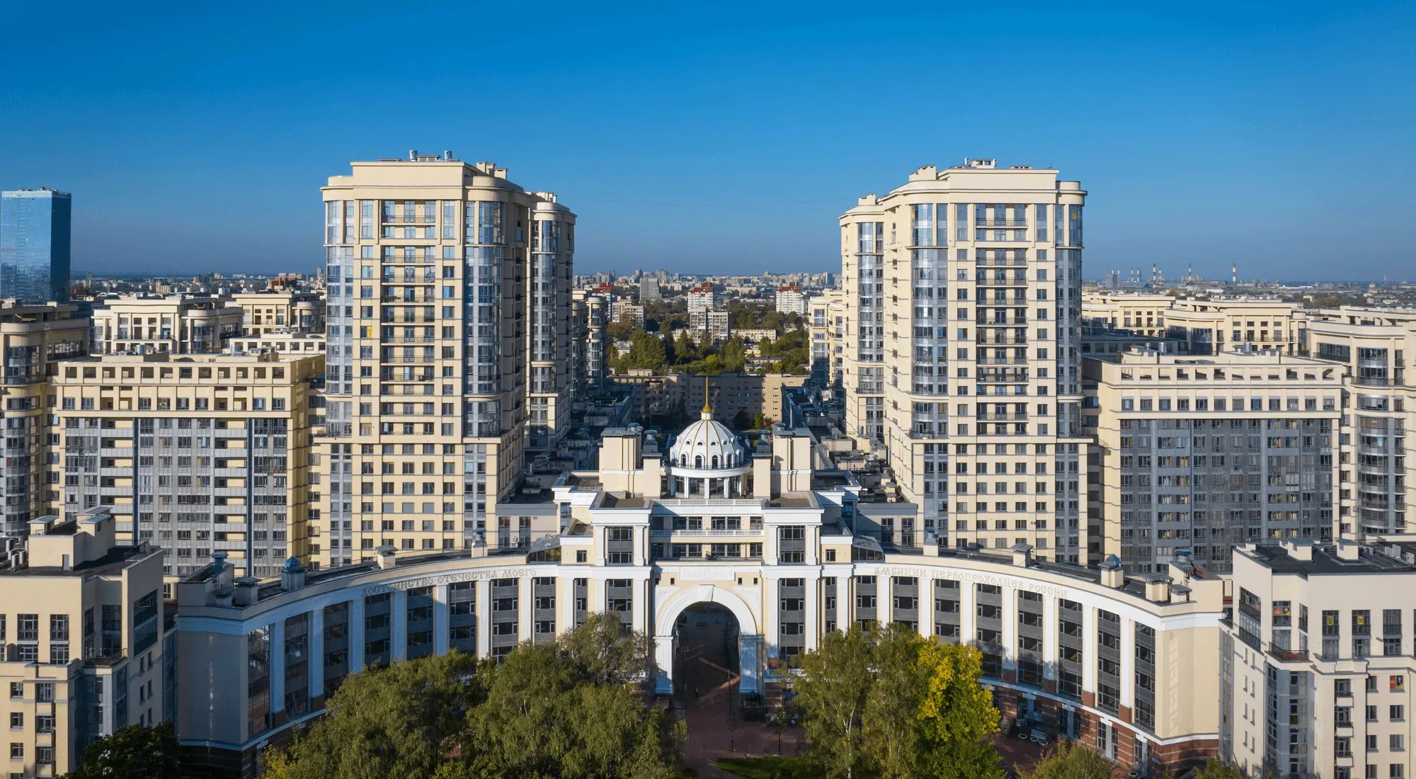 Корпус с аркой и куполом на первом плане, за ним две светлые башни и корпуса пониже