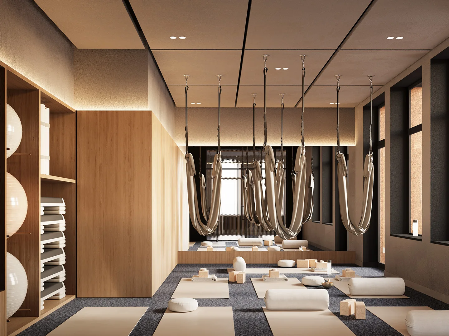 Зал йоги клуба резидентов: подвесные гамаки под потолком с точечными светильниками, коврики и валики на полу, деревянные стеллажи с фитболами