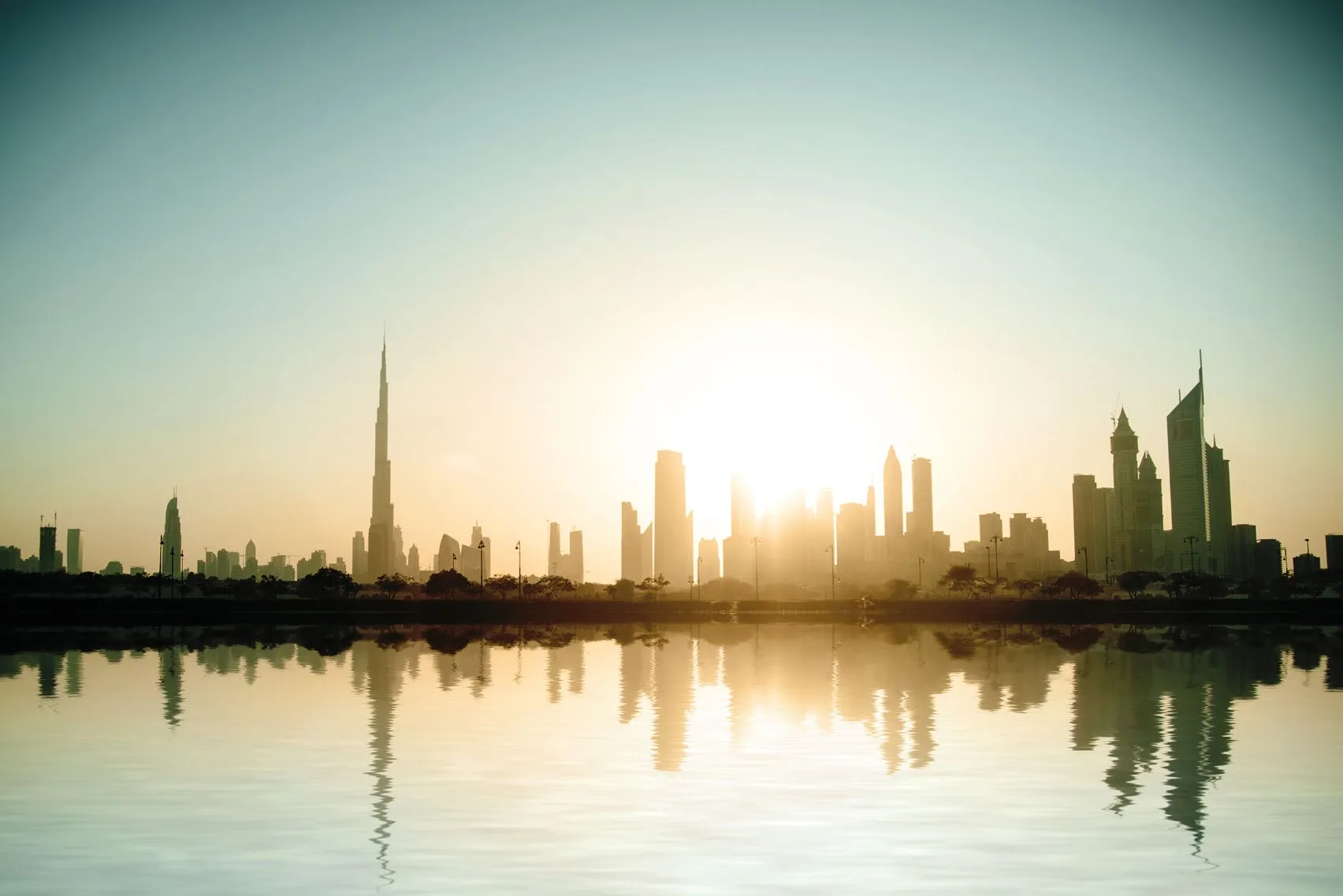 Силуэт Дубая с Burj Khalifa на закате над водой