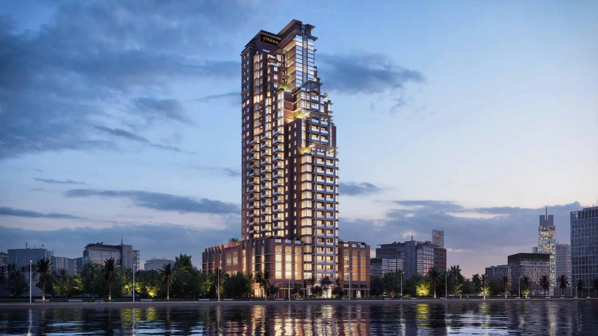 Riva Residence вечером: освещённая башня отражается в воде