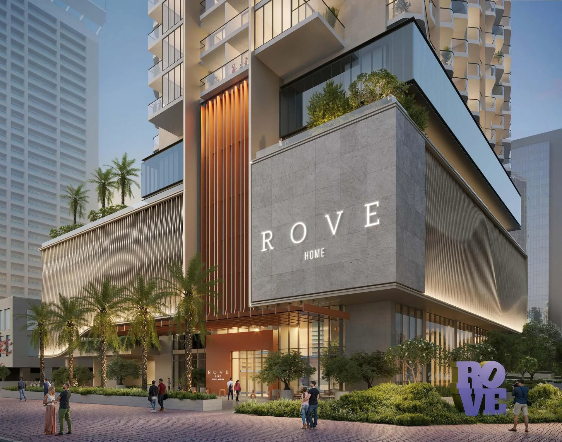 Вход в Rove Home вечером: фасад с буквами ROVE HOME и пальмы