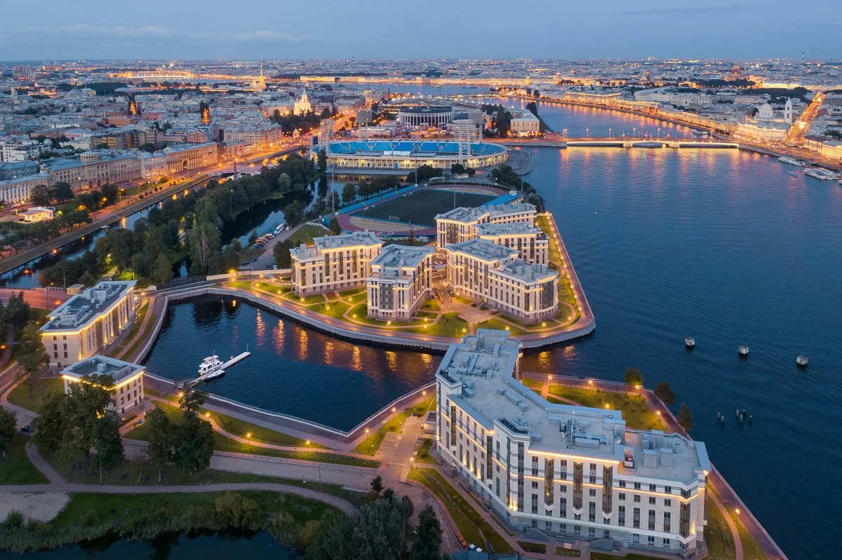 Петровский остров с воздуха: корпуса Royal Park у бухты, стадион «Петровский», за ним мост и крыши центра Петербурга