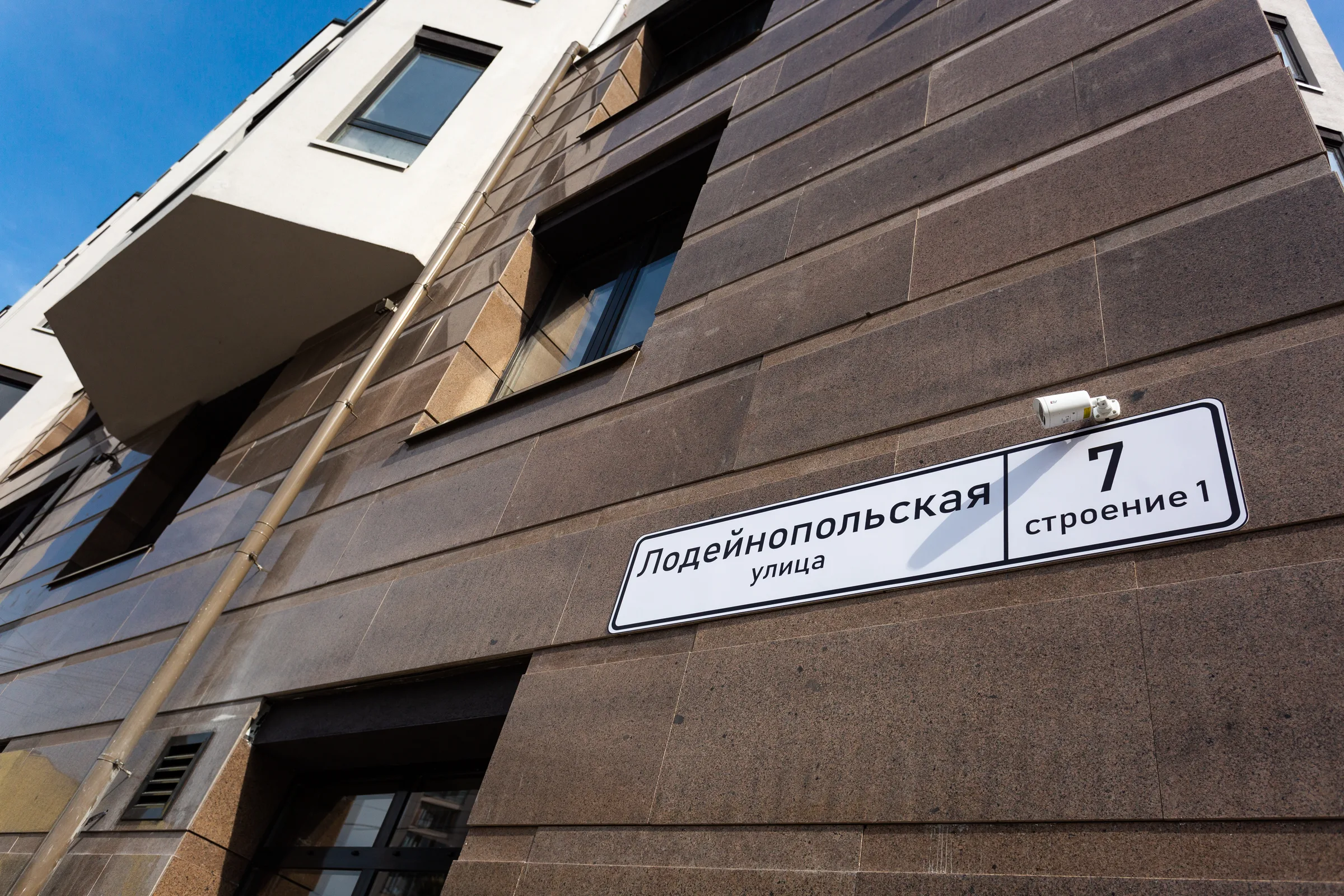 Нижний этаж дома крупно: плиты тёмного гранита и адресная табличка с надписью «Лодейнопольская улица»