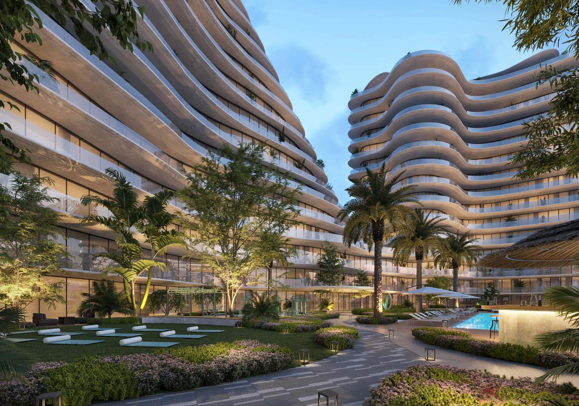 Двор The Beach Residences вечером: газон, дорожки и бассейн между башнями