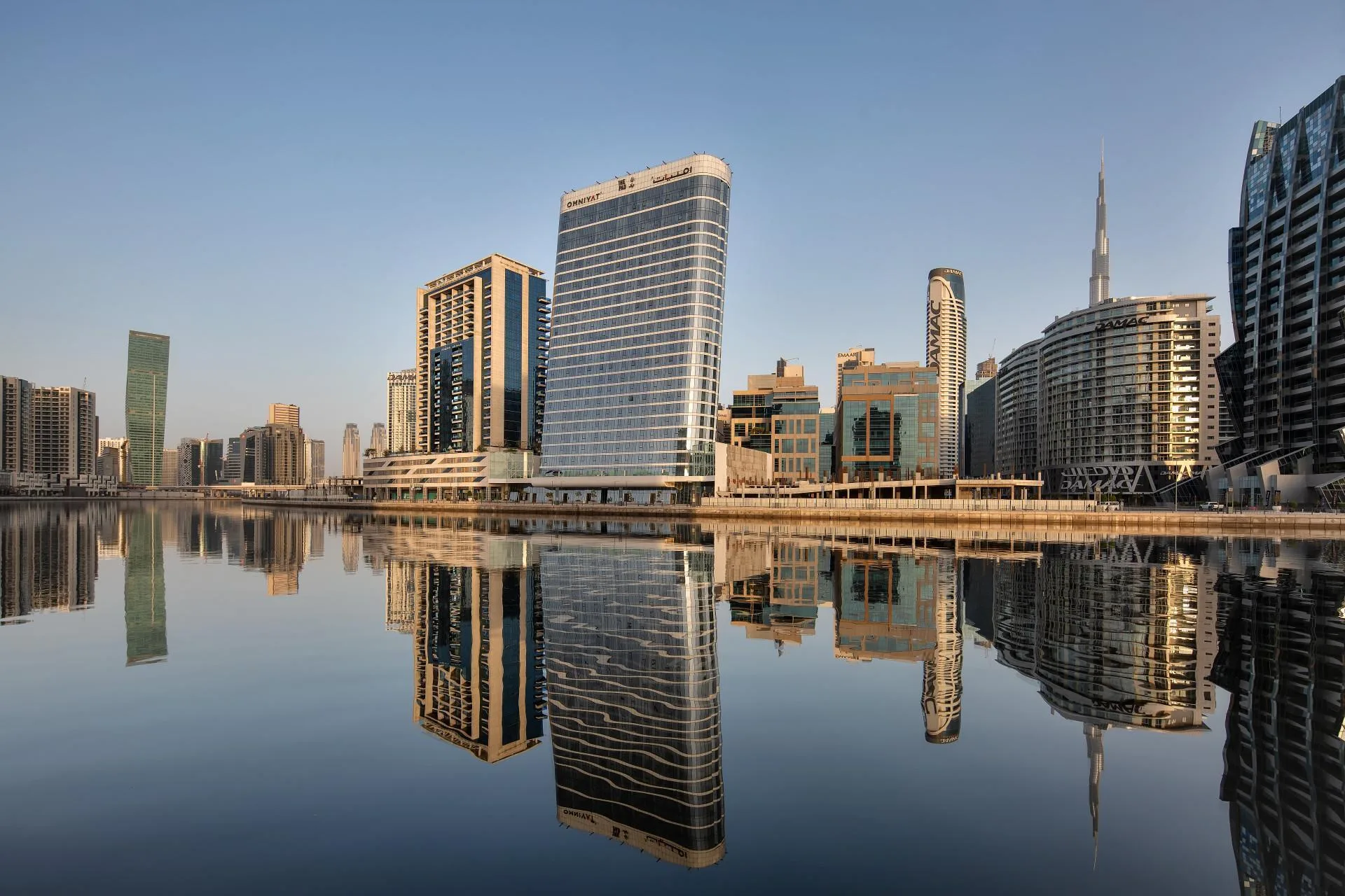 Утренний Business Bay над гладкой водой канала, вдали Burj Khalifa